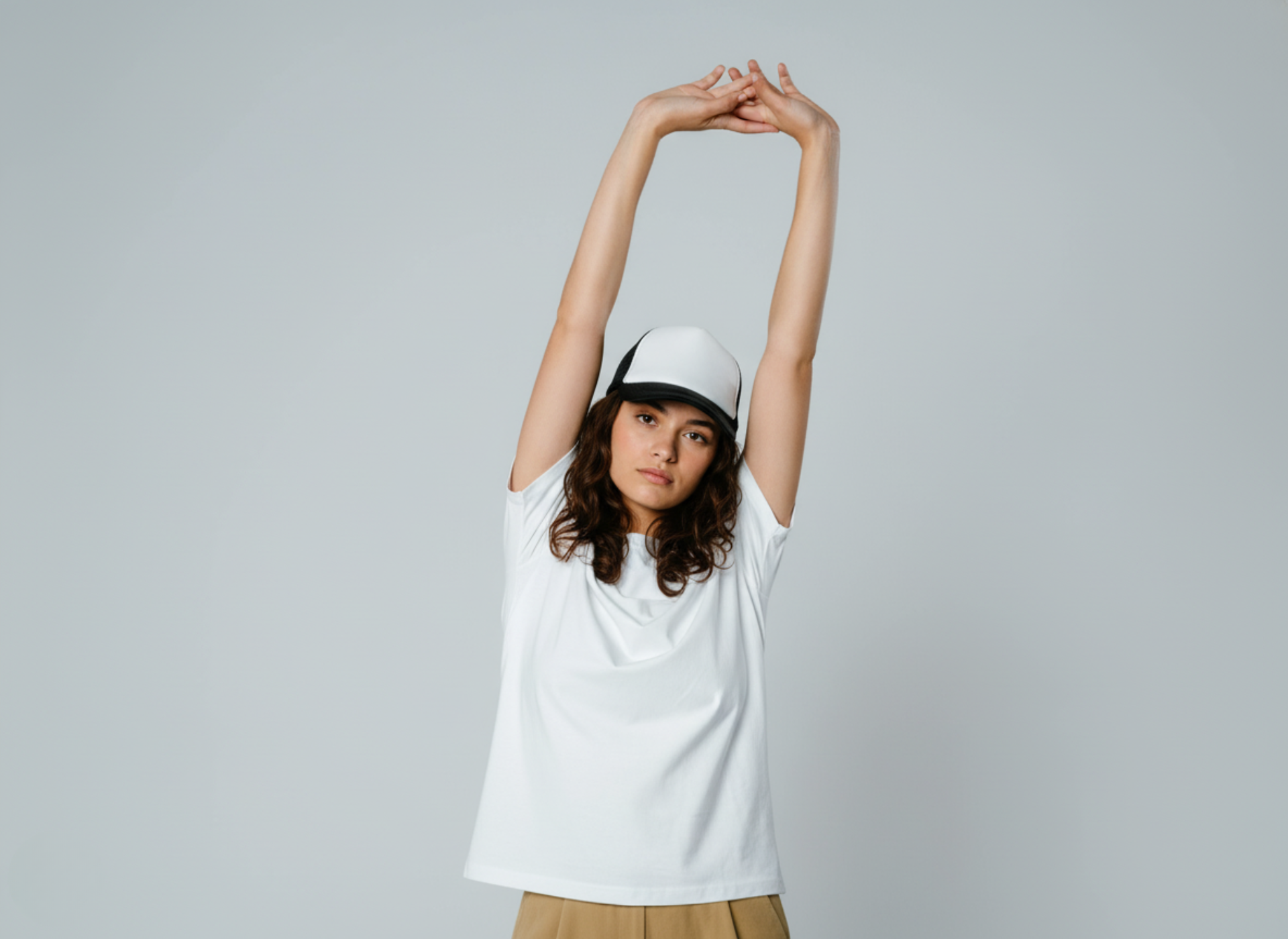 Woman wearing a white cap and white t-shirt against a gray background