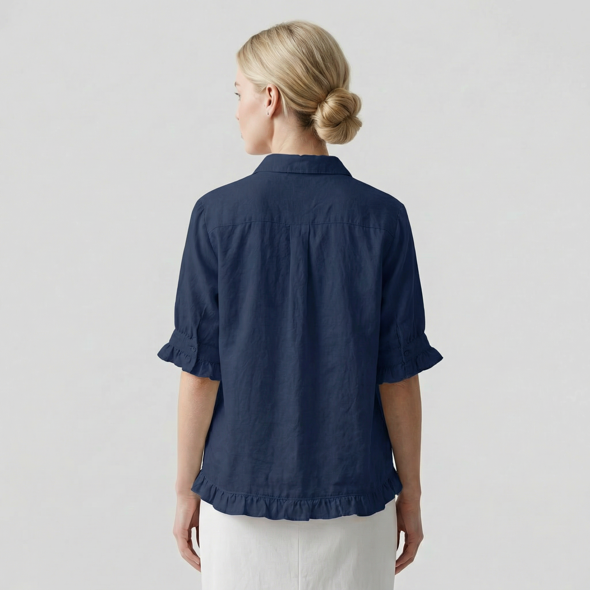 Person wearing a navy blue shirt with rolled-up sleeves on a light gray background
