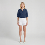 Woman wearing a navy shirt and white shorts on a plain background