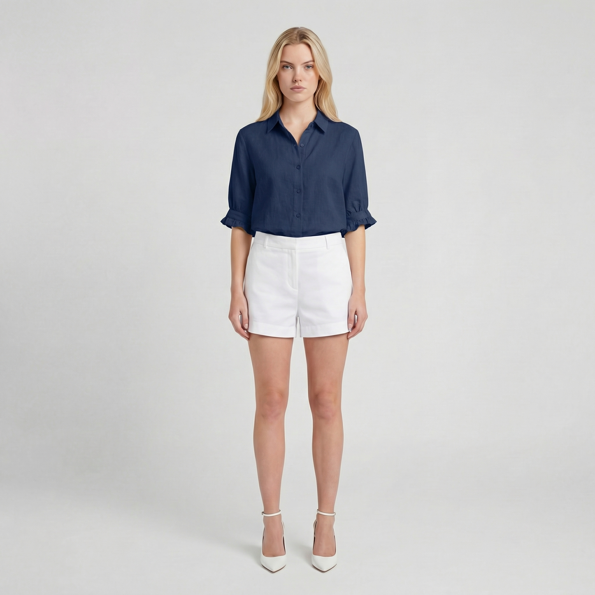Woman wearing a navy shirt and white shorts on a plain background