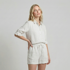 Woman wearing a white shirt and shorts on a plain background