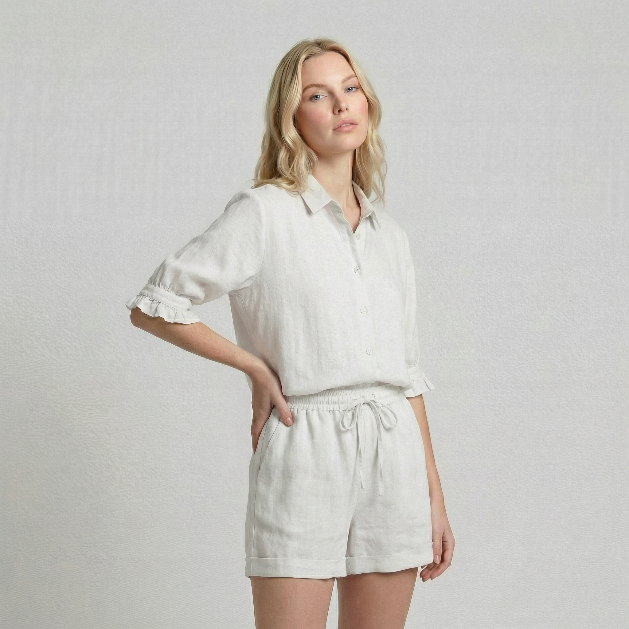 Woman wearing a white shirt and shorts on a plain background