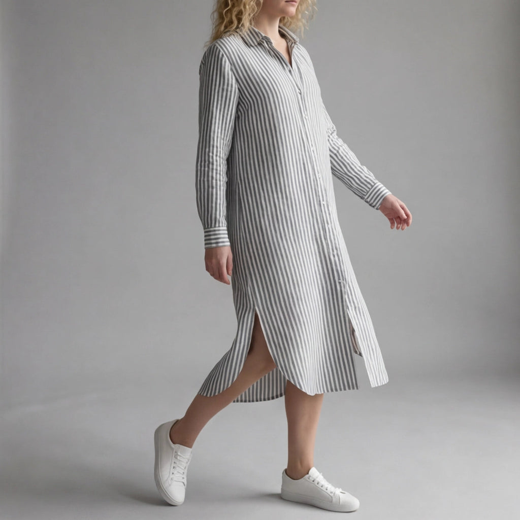 Woman wearing a long striped dress with white sneakers on a gray background