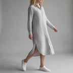 Woman wearing a long striped dress with white sneakers on a gray background