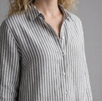 Close-up of a person wearing a gray and white striped shirt against a gray background