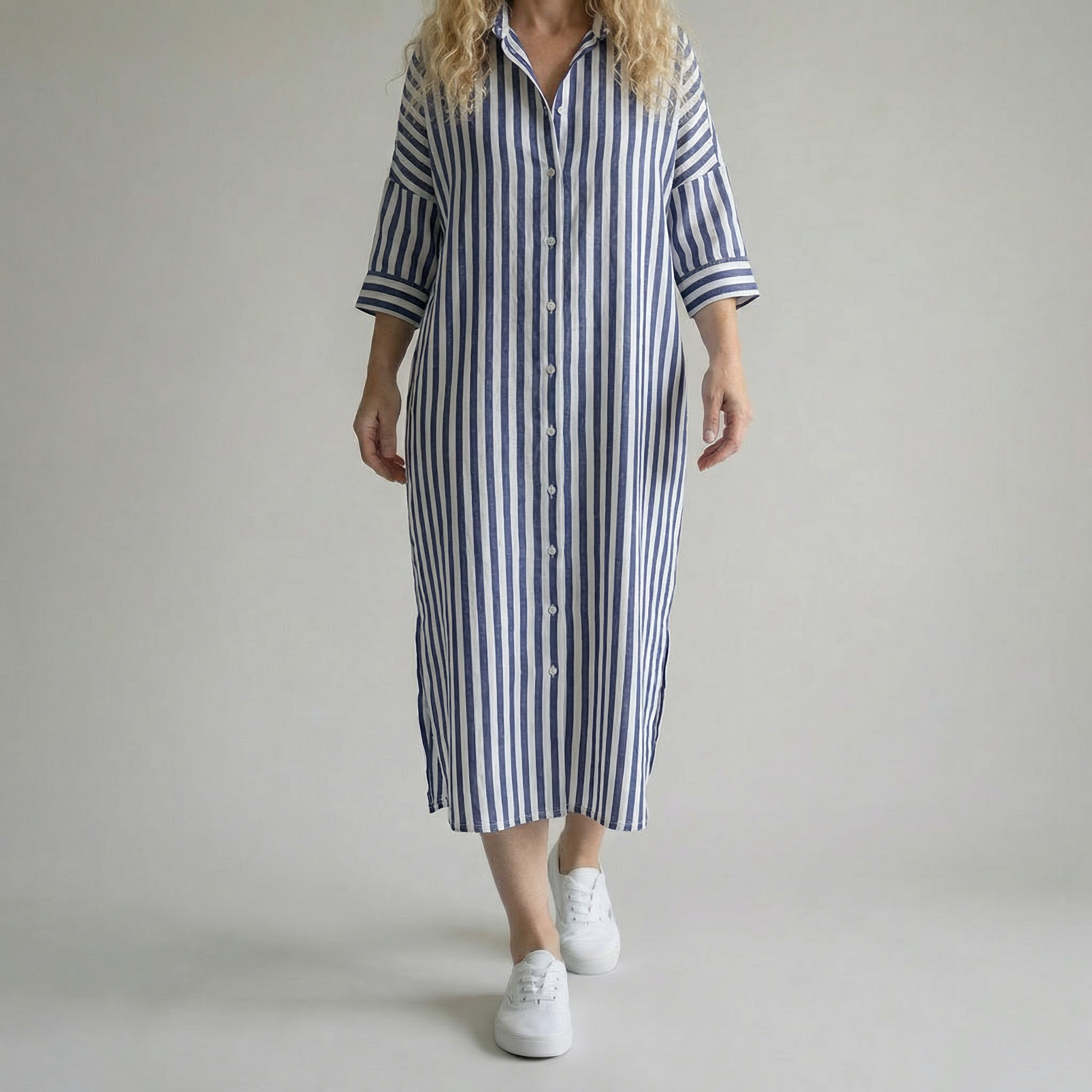 Person wearing a blue and white striped dress on a plain background
